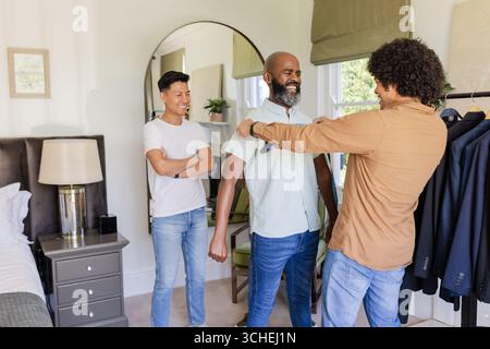 Männlicher Schneider passt Afroamerikaner für Anzug im Schlafzimmerbereich, mit Maßband, Kopierraum Stockfoto