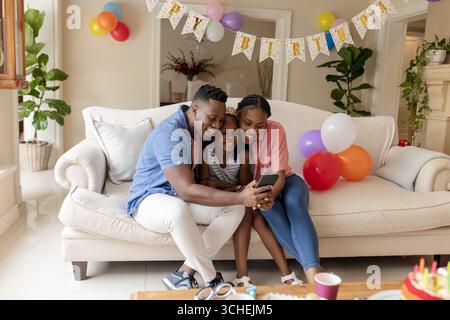 Auf der Party feiert Familie zu Hause Geburtstag, lächelt und nimmt Selfie auf dem Sofa Stockfoto