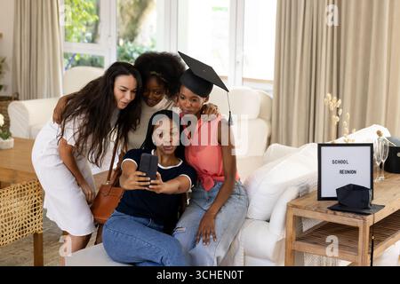 Verschiedene Freundinnen machen während des Schulwiedersehens zu Hause Selfie und feiern mit Lächeln und Freude Stockfoto