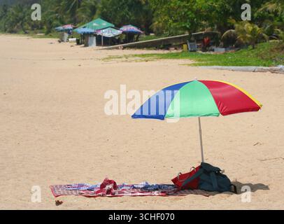Phuket, Thailand-31. März 2016: Unbekannte Menschen, die sich sonnen und an den Bäumen auf dem Sand am Karon Beach sitzen Stockfoto