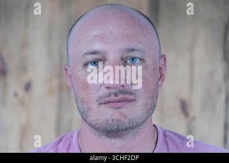 Closeup Shooting für mittleren Alters kaukasischen glatzköpfige Mann, der gerade in die Kamera schauen. Menschen und Lifestyle Konzept. Porträt der Mann mittleren Alters im Innenbereich Stockfoto