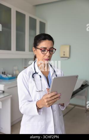 Ernsthafte reife Frau im Gesundheitswesen, die ein Tablet am Arbeitsplatz verwendet Stockfoto