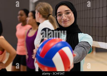Diverse weibliche Mannschaft hält Volleyball auf dem Fitnessplatz mit Netz, Kopierraum Stockfoto