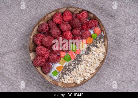 Smoothie in Kokosnussschale mit Himbeeren, Haferflocken, kandierten Früchten und Chiasamen zum Frühstück, Nahaufnahme. Das Konzept der gesunden Ernährung, Superfood. T Stockfoto