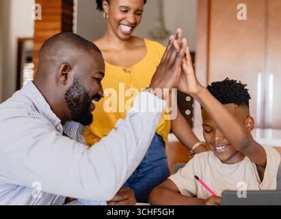 Afroamerikanische Familie feiert Erfolg zu Hause, Vater und Sohn sind High-Five Stockfoto