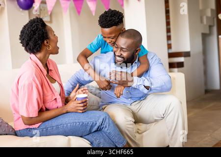 Auf der Party genießen glückliche Familien einen verspielten Moment auf der Couch zu Hause Stockfoto