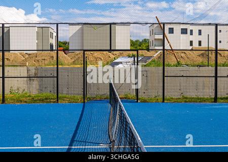 Leerer Padel-Sportplatz mit blauem Boden und Netz in der Mitte Stockfoto