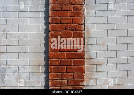 Dieses Bild zeigt eine strukturierte Wand mit einem auffälligen Kontrast zwischen roten und weißen Ziegelmustern, wodurch ein optisch ansprechender abstrakter Hintergrund entsteht Stockfoto