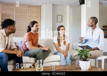 Verschiedene Gruppen diskutieren Ideen im Wohnzimmer, führen nachdenkliche Gespräche, zu Hause Stockfoto