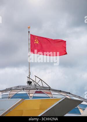 Die sowjetische Flagge fliegt an einem bewölkten Morgen über dem belarussischen Staatlichen Museum der Geschichte des Großen Vaterländischen Krieges Stockfoto