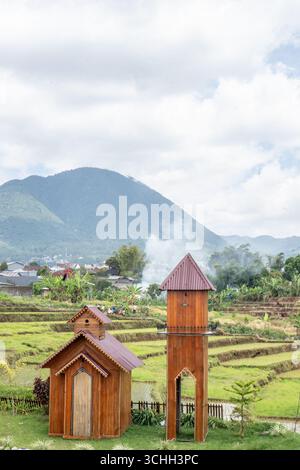 Eine kleine Holzkapelle und ein Glockenturm inmitten von Reisterrassen Stockfoto