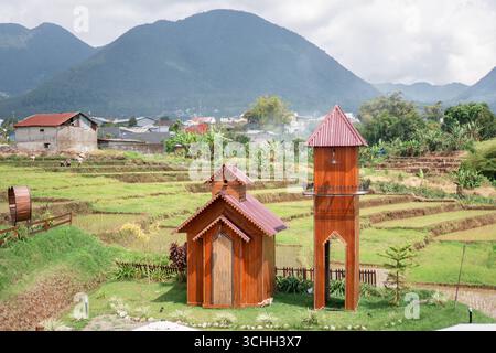 Eine kleine Holzkapelle und ein Glockenturm inmitten von Reisterrassen Stockfoto