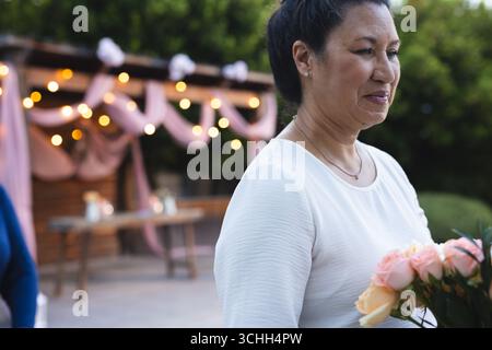 Lächelnde Frau mit Blumenstrauß bei Feierlichkeiten im Freien mit festlicher Dekoration Stockfoto