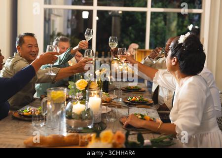 Senioren, die mit Weingläsern auf einer eleganten Dinner-Party anstoßen und gemeinsam feiern Stockfoto