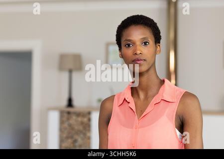 Selbstbewusst zu Hause, Afroamerikanerin in Korallenbluse, die nachdenklich aussieht, Kopierraum Stockfoto