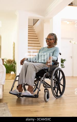 Afroamerikanerin im Rollstuhl lächelt zu Hause, genießt entspannte Momente, Kopierraum Stockfoto