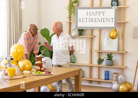 Seniorenfreunde feiern den Ruhestand mit Gesprächen und Snacks auf der Heimfeier Stockfoto