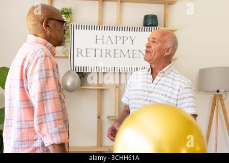 Seniorenfreunde feiern gemeinsam den Ruhestand und plaudern fröhlich zu Hause Stockfoto
