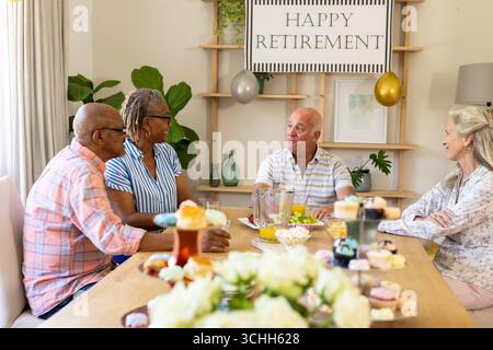 Seniorenfreunde feiern den Ruhestand mit Gesprächen und Snacks zu Hause Stockfoto