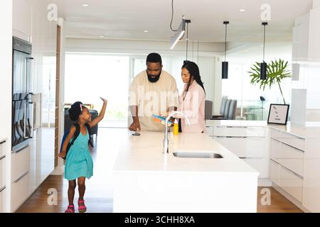 Glückliche Familie, die Zeit in der modernen Küche genießt, glückliche Eltern lesen während Kind spielt, zu Hause Stockfoto