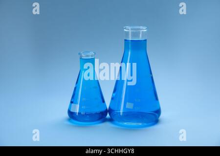 Kolben mit heller Flüssigkeit auf hellblauem Hintergrund mit Farbverlauf Stockfoto