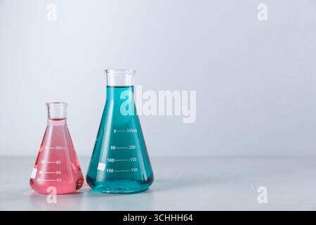 Kolben mit Farbflüssigkeiten auf hellem Hintergrund. Leerzeichen für Text Stockfoto