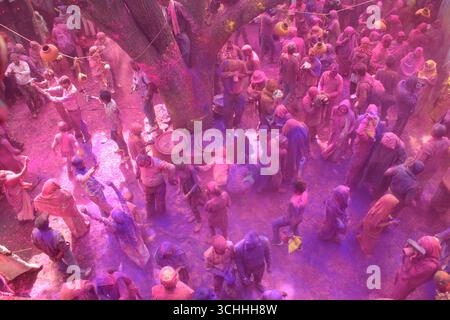 Die Atmosphäre ist mit den Farben von Holi erfüllt, während die Menschen während des Hindu-Festivals in Vrindavan, Mathura, Indien tanzen. Stockfoto