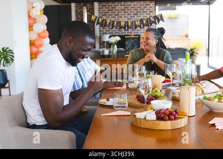 Wir feiern den Ruhestand, eine vielfältige Gruppe genießt Essen und Lachen zu Hause Stockfoto