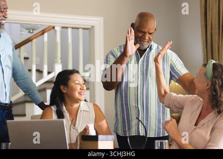 Senioren feiern zu Hause Erfolg, geben High Fives und lächeln zusammen Stockfoto