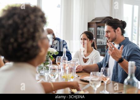 Freunde lachen und unterhalten sich bei der Hochzeitsfeier am Esstisch Stockfoto