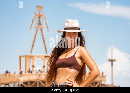 Frau posiert vor dem brennenden Mann Effigy in der Wüste Nevada Stockfoto