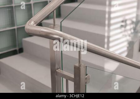 Ein elegantes Edelstahlgeländer ergänzt ein modernes Treppenhaus mit Glaspaneelen, das minimalistisches Design in einem modernen Ambiente bietet. Die LIG Stockfoto