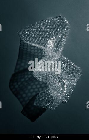 Nahaufnahme der Luftpolsterfolie, die geometrische Schatten auf einer Oberfläche erzeugt. Abstrakte Minimaltextur bei monochromem Licht. Stockfoto