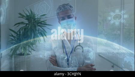 Der stehende Arzt kreuzt Arme in der Klinik mit Maske und Stethoskop mit holographischem Display Stockfoto