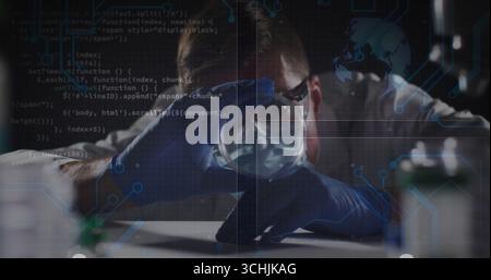 Untersuchung eines Forschers mit Labormantel und Handschuhen zur Analyse des Kolbens auf dem Labortisch mit Code-Overlays Stockfoto