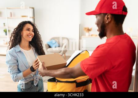 Schwarzer Lieferer nimmt die Box aus dem Thermorucksack Stockfoto