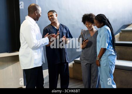 Medizinische Fachkräfte in Scrubs diskutieren im Krankenhaus, lächeln, in der Konferenzhalle Stockfoto