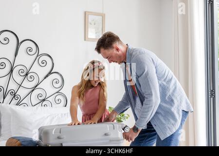 Vater und Tochter packen zusammen Koffer zu Hause und bereiten sich auf den Urlaub vor Stockfoto