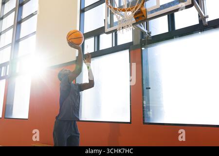 Mann in Sportswear, der auf den Basketball springt und den Ball unter den Fenstern des Fitnessstudios hält, Kopierraum Stockfoto