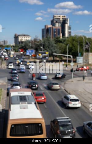 Eine verschwommene, hochwinkelige und vertikale Aufnahme einer belebten Stadtstraße mit einem Bus und verschiedenen Autos. Das Bild erfasst die dynamische, verschwommene Bewegung der täglichen tr Stockfoto