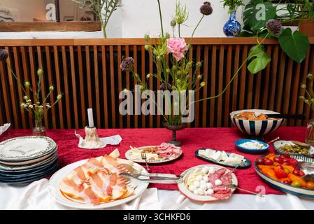 Der elegant gestaltete Tisch bietet verschiedene Vorspeisen wie Aufschnitt, Käse und Gemüse. Die Einrichtung umfasst Blumendekorationen und feine Ta Stockfoto