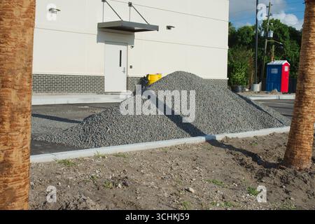 Haufen losen Kies in der Nähe eines im Bau befindlichen Gebäudes, auf einer Baustelle für Pflasterarbeiten und Bauzwecke. Umgebung Stockfoto