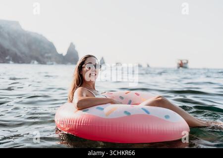 Frau, schwimmend, Meer, glückliche Frau, die Sommerurlaub auf Donut aufblasbar genießt. Stockfoto