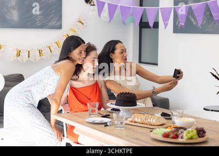 Mit Selfie feiern drei junge Frauen auf der Geburtstagsfeier drinnen Stockfoto