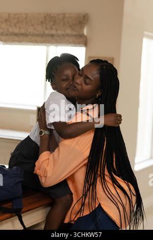 Afroamerikanische Mutter umarmt ihr Kind zu Hause und teilt einen liebevollen Moment miteinander Stockfoto