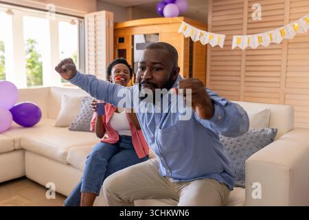 Tanzen und jubeln, fröhliches Paar feiert Geburtstag im dekorierten Wohnzimmer Stockfoto