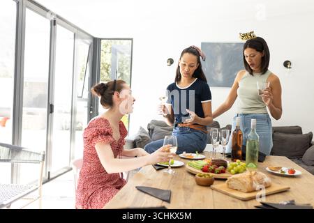 Drei junge Frauen unterhalten sich und lachen, genießen einen sonnigen Nachmittag zu Hause Stockfoto