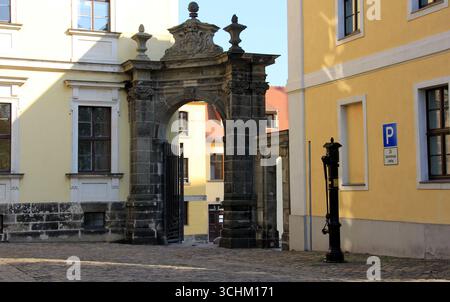 Barockes Tor und altmodische Straßenwasserpumpe, installiert in einem Kopfsteinpflasterhof nahe dem Domplatz in Magdeburg Stockfoto