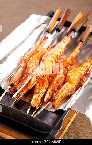 Gegrillte Garnelenspieße im asiatischen Stil auf einer mit Folie gefütterten Pfanne Stockfoto