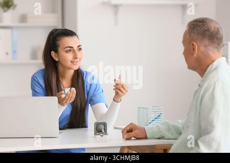 Ärztin zeigt Hörgerät in der Klinik Stockfoto